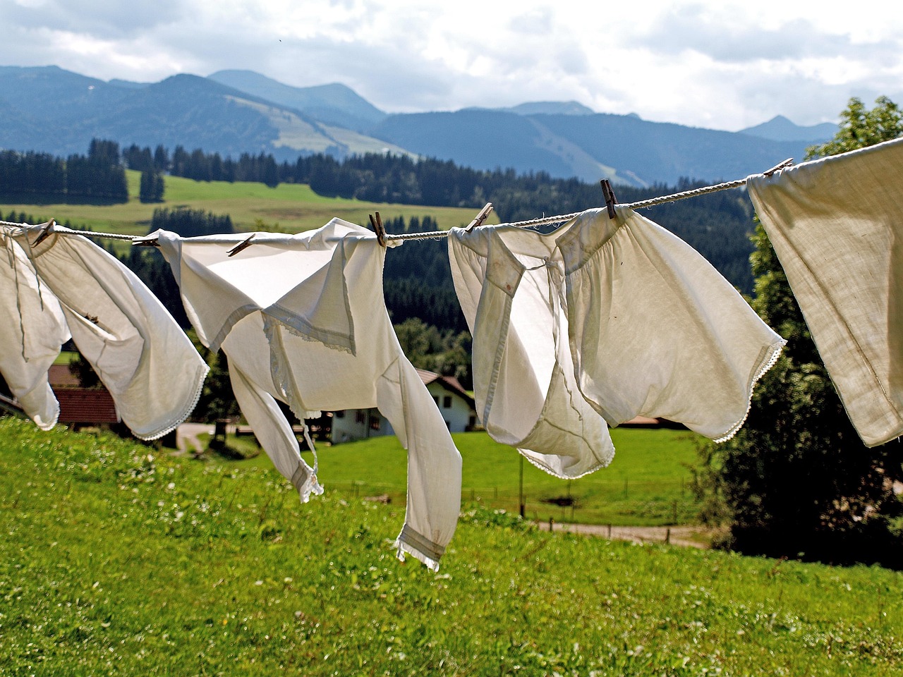 Un bambino gioca all'aperto con vestiti macchiati di erba, mentre una madre prepara un rimedio naturale.