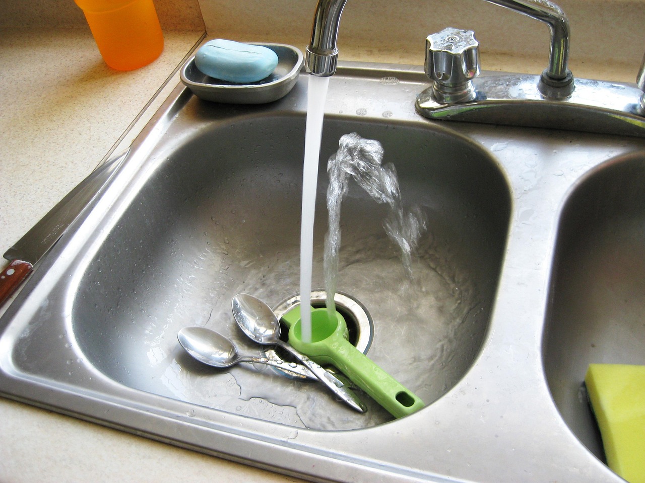 Immagine di un lavandino con acqua stagnante e attrezzi per la riparazione.